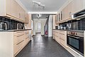 Moderne Küche in Nord-Norwegen: helle Holzschränke, dunkle Bodenfliesen, stilvolle schwarze Fliesenrückwand, integrierter Backofen, Edelstahlspüle, und Wasserkocher. Geräumig und einladend, ideal für Angelurlaube.