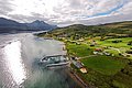 Luftaufnahme einer malerischen Bucht in Nord-Norwegen mit Fjord, grünen Wiesen und sanften Hügeln. Ideal für Angelreisen, bietet die Region Abgeschiedenheit und atemberaubende Natur, perfekt für unvergessliche Angelabenteuer und Entspannung.