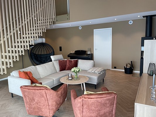 Modernes Wohnzimmer in Norwegen, Hitra: Helle Sofas, gemütliche Sessel, Holztreppe, Hängesessel, Kamin und eleganter Dekor. Perfekt für Entspannung und Angelabenteuer. Ideal für Angelurlaub in skandinavischem Ambiente.