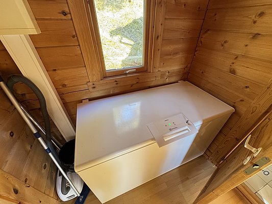 Kleiner Abstellraum in Hitra, Norwegen: Holzwände, Fenster, weiße Gefriertruhe von Electrolux. Ideal zum Lagern von Fängen nach erfolgreichem Angelurlaub in malerischer Naturumgebung. Rustikal und funktional für Angler.