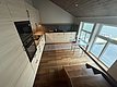 Moderne skandinavische Küche in Nord-Norwegen mit Holzfußböden und großen Fenstern mit Blick auf das Wasser. Helle Holzmöbel und minimalistische Einrichtung schaffen eine gemütliche Atmosphäre. Ideal für erholsame Angelurlaube.
