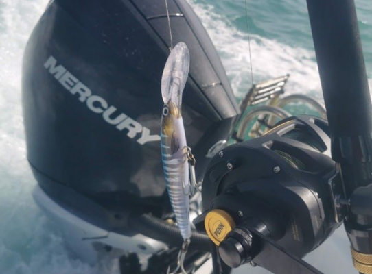 Angelrolle und Köder in Aktion vor einem Motorboot auf offener See in Nord-Norwegen. Ideale Bedingungen für Meeresangeln, umgeben von spritzender Gischt und Freiheit des Wassers. Abenteuerlicher Angelurlaub.