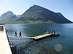 Klarer Fjord in Nordland, Norwegen: Steg mit Anglern vor beeindruckender Bergkulisse bei Sonnenschein. Ideal für Angelurlaub und Naturerlebnis. Perfekte Kombination aus Abenteuer und Entspannung in traumhafter Landschaft.