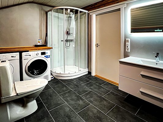 Ein modernes Badezimmer in Hitra, Norwegen, mit Dusche, Waschmaschine und Trockner. Perfekt für Angler, die nach einem erfolgreichen Tag im Angelurlaub Komfort und Bequemlichkeit suchen. Sorglos angeln und entspannen.