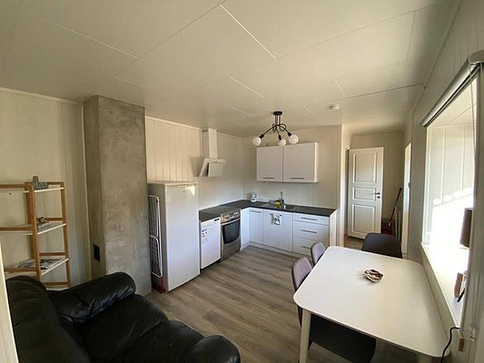 Gemütliche, moderne Ferienwohnung in Nord-Norwegen. Küche mit Herd, Kühlschrank und Esstisch. Ideal für Angelurlaub, bietet Komfort und Bequemlichkeit nach einem langen Tag am Meer. Helle, einladende Atmosphäre mit stilvollem Interieur.