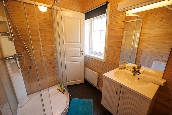 Modernes Badezimmer in Nordland, Norwegen, mit gemütlicher Holzwandverkleidung, Dusche, weißem Waschtisch und Fenster für natürliches Licht. Ideal für komfortable Angelunterkunft.