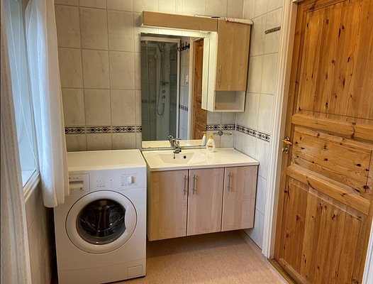 Helle Badezimmer in Hitra, Norwegen: Waschmaschine, Waschbecken mit Spiegel und Holzdetails schaffen Komfort und Funktionalität. Ideal für Angler mit sauberem und praktischem Rückzugsort nach einem erlebnisreichen Tag am Wasser.