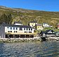 Ein idyllisches Küstendorf in Nord-Norwegen mit bunten Häusern und einem klaren Fjord unter blauem Himmel. Perfekte Kulisse für Angelreisen, Naturgenuss und Erholung. Ideal für Freizeitangler, die Abenteuer und Entspannung suchen.