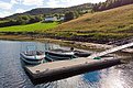 Ein idyllischer Anblick in Hitra, Norwegen: Boote ruhen an einem Steg im klaren Wasser, umgeben von grünen Wiesen und Wäldern. Perfekter Ausgangspunkt für einen unvergesslichen Angelurlaub im malerischen Skandinavien.
