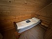 Gemütliches, holzverkleidetes Schlafzimmer in Hitra, Norwegen. Einzelbett mit Bettwäsche und Leselampe, ideal für erholsamen Angelurlaub. Ruhiger Rückzugsort nach einem Tag voller Abenteuer in der atemberaubenden Natur Norwegens.