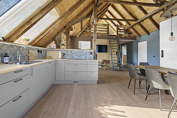 Moderne skandinavische Loft-Küche in Südwest-Norwegen, mit grauen Schränken, Holzbalken und viel natürlichem Licht. Perfekt für gemütliche Angelurlaube in inspirierender Umgebung. Ideal, um nach einem erfolgreichen Angeltag zu entspannen und zu kochen.