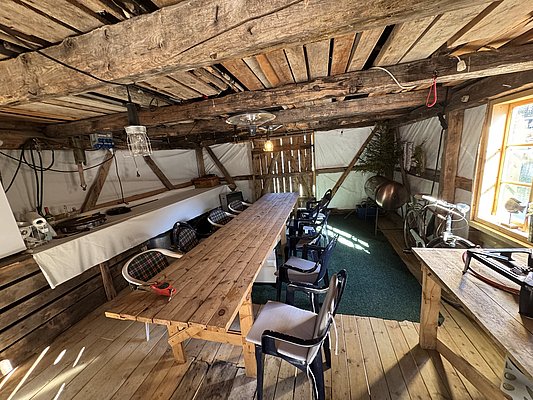 Rustikaler Raum in Hitra, Norwegen, mit Holztisch und Stühlen. Gemütliche Atmosphäre, ideal für Angelgruppen-Treffen nach erfolgreichen Touren. Holzbalken und natürliche Materialien schaffen authentisches, heimeliges Flair auf Angelreisen. Perfekt für gesellige Abende.