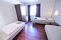 Gemütliches Zimmer in Hitra, Norwegen: Helle Holzböden, zwei Betten, Schrank und Tageslicht durch Fenster. Ideal für Angelreisende, die Komfort und Entspannung nach einem Tag am Wasser suchen. Perfekter Rückzugsort in Norwegens Natur.