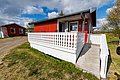Kleine rote Holzhütte in der Region Hitra, Norwegen, mit gemütlicher Veranda und Rollstuhlrampe, umgeben von malerischer Landschaft. Perfekte Unterkunft für Angelreisen und Naturerlebnisse.