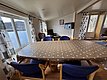 Gemütliches Wohnzimmer in Hitra, Norwegen: Großer Esstisch mit blauer Bestuhlung, Blick auf den Fjord durch breite Fenster, entspannende Sitzecke und Tür zur Terrasse. Ideal für erholsamen Angelurlaub.