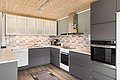 Moderne Küche in Nordland, Norwegen, mit stilvollem Design: graue Schränke, helle Holzdecken, gestaltete Fliesenwände und hochwertige Geräte. Perfekt für Anglerurlaube oder entspannte Kochabende nach einem erfolgreichen Angelausflug.