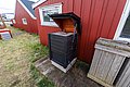Rote Holzhäuser in Hitra, Norwegen, mit Außenschränken neben gepflegter Grasfläche. Die rustikale Architektur spiegelt die traditionelle skandinavische Bauweise wider, ideal für einen Angelurlaub in der idyllischen Natur Norwegens.