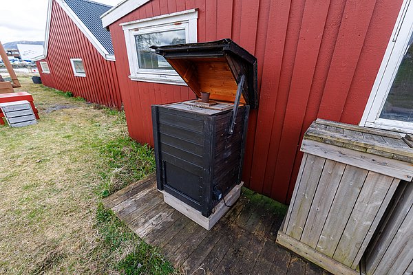 Rote Holzhäuser in Hitra, Norwegen, mit Außenschränken neben gepflegter Grasfläche. Die rustikale Architektur spiegelt die traditionelle skandinavische Bauweise wider, ideal für einen Angelurlaub in der idyllischen Natur Norwegens.