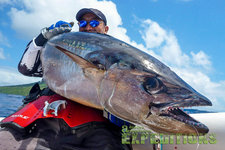 Ein stolzer Angler präsentiert einen beeindruckenden Thunfisch vor der Küste Tansanias unter klarem Himmel, ideal für sportliches Meeresangeln. Perfekte Bedingungen für Abenteuer und große Fänge.