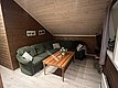 Gemütliches Wohnzimmer in Nord-Norwegen mit Ecksofa, Holzwänden, zwei Fotos, Holztisch und Dekopflanzen. Ideal für entspannte Angelreise-Pausen bei Andrees Angelreisen. Rustikale Atmosphäre für erholsame Stunden nach Abenteuern am Meer.
