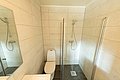 Helles, modernes Bad in Nord-Norwegen mit begehbarer Dusche, gefliesten Wänden und Toilette. Perfekt für Angler auf Erholungstour.