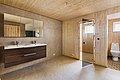 Ein modernes Badezimmer aus Holz in Nordland, Norwegen. Doppelte Waschbecken, Glasdusche, helle Fliesen und natürliche Holzverkleidung sorgen für ein helles, einladendes Ambiente. Perfekt für einen erholsamen Angelurlaub im skandinavischen Stil.