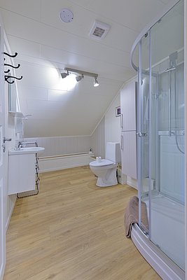 Helles Badezimmer in Nordland, Norwegen: Moderne Dusche, helles Holzlaminat, weiße Wände. Ideal für Anglerunterkünfte, bietet Komfort nach einem erlebnisreichen Tag beim Meeresangeln. Perfekte Kombination aus skandinavischem Design und Funktionalität.