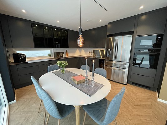 Moderne Küche in Hitra, Norwegen, mit schwarzer Einbauküche, elegante Beleuchtung und stilvollem Esstisch. Ideal für Angelurlaube in der Region. Perfekt ausgestattet für gemütliche Abende nach erfolgreichen Angelausflügen.