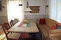 Gemütliche Sitzecke in traditionellem norwegischen Stil, Hitra. Holztisch mit Bank und Stühlen, farbigem Läufer und goldenen Kerzenständern. Ideal für Angelurlauber, die gemütliche Unterkünfte suchen. Skandinavisches Design trifft auf Wohlfühlambiente.
