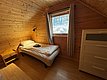 Ein gemütliches Schlafzimmer in einer Holzhütte auf Hitra, Norwegen, bietet Holzverkleidung, ein Einzelbett, einen Nachttisch und einen Ausblick in die Natur. Perfekt für entspannende Angelurlaube.