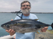 Ein glücklicher Angler präsentiert stolz seinen großen Fischfang am malerischen Ufer von São Vicente, Kapverden. Perfekter Angelurlaub für Abenteurer und Genießer in exotischer Umgebung.