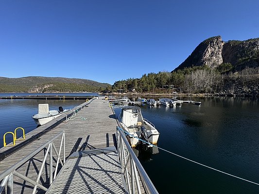 Der Pier in Hitra, Norwegen, bietet klare, ruhige Gewässer und eine beeindruckende Bergkulisse. Perfekter Ausgangspunkt für Angelabenteuer auf dem malerischen Fjord. Ideal für entspannte Tage in der Natur.