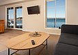 Modernes Wohnzimmer in Hitra, Norwegen: Helle Holzmöbel, Panoramablick auf das ruhige, blaue Wasser. Entspannende Atmosphäre für Angelurlaub. Große Fenster bieten atemberaubende Aussicht. Ideal für Naturfreunde und Angler.