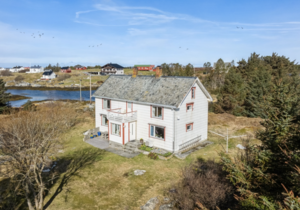 Weißes Holzhaus auf Hitra, Norwegen, umgeben von Wald und Blick auf einen ruhigen Fjord. Perfekter Angelurlaub mit unberührter Natur und gelassener Atmosphäre. Ideal für Entspannung und Abenteuer.