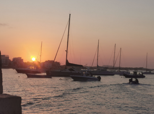 Segelboote im Hafen von São Vicente, Kapverden, bei Sonnenuntergang. Orangefarbener Himmel spiegelt sich im ruhigen Meer und schafft eine friedliche, maritime Szenerie. Perfekt für Angelreisen und maritime Abenteuer.