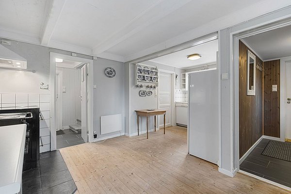 Gemütliches skandinavisches Interieur in Nordland, Norwegen: offener Raum mit Holzboden, weißer Küche, Wanddeko und einem kleinen Tisch. Perfekter Ausgangspunkt für Angelreisen und Naturerlebnisse im hohen Norden!