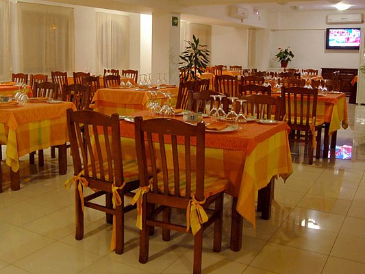 Ein gemütliches Restaurant mit orange-gelb gedeckten Tischen und hölzernen Stühlen, das auf Gäste wartet. Ein gemütliches Restaurant mit orange-gelb gedeckten Tischen und hölzernen Stühlen, das auf Gäste wartet.