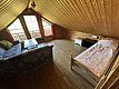 Ein gemütliches Dachzimmer in Hitra, Norwegen, mit Holzverkleidung und großen Fenstern. Blick auf Balkon, Sofa, Bett und Tisch schaffen eine einladende Atmosphäre für entspannte Angelurlaube. Ideal für Ruhe und Erholung.
