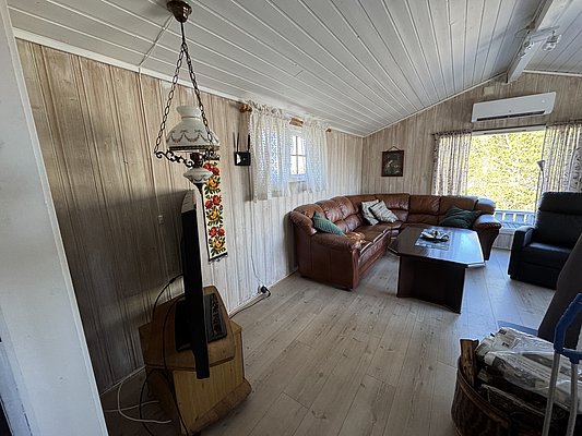 Gemütliches Wohnzimmer in einem norwegischen Ferienhaus auf Hitra, Norwegen. Holzwände, bequeme Ledercouch und rustikale Dekoration schaffen eine einladende Atmosphäre für Angelurlaube in malerischer Umgebung. Ideal zum Entspannen nach einem erlebnisreichen Tag auf dem Wasser.
