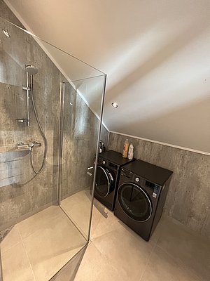 Modernes Badezimmer in Nordland, Norwegen, mit eleganter Dusche und integrierter Waschmaschine. Ideal für komfortable Angelurlaube, die Bequemlichkeit mit Funktionalität verbinden. Perfekte Unterkunft für entspannte Erholung nach erlebnisreichen Tagen am Wasser.