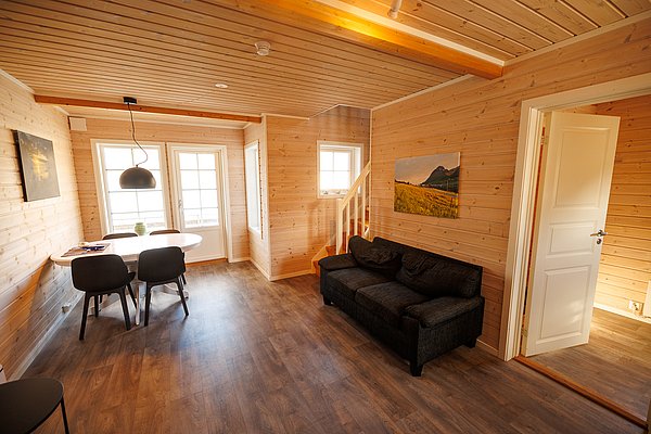 Gemütliches skandinavisches Ferienhaus in Nordland, Norwegen mit moderner Holzeinrichtung. Helle, einladende Räume mit Essbereich und Sofa. Ideal für Angelreisen und Naturerlebnisse im nordischen Flair. Perfect für einen erholsamen Angelurlaub.
