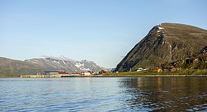 Küstenpanorama von Nord-Norwegen: Klare Gewässer und beeindruckende Berglandschaft mit kleinen Küstendörfern. Perfekte Kulisse für Angelreisen und Naturerlebnisse, die Abenteuerlust und Entspannung vereinen. Ideal für Angler und Naturliebhaber.