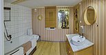 Gemütliches Badezimmer in Nordland, Norwegen: Moderne Einrichtung mit Holzelementen, Badewanne, rundem Spiegel und künstlerischen Wandbildern. Warme, einladende Atmosphäre ideal für Entspannung nach erlebnisreichem Angelabenteuer. Perfekter Rückzugsort im skandinavischen Stil.