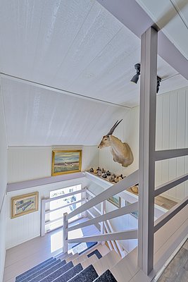 Heller Treppenaufgang in nordischem Stil mit Jagdtrophäe und Gemälden zur Dekoration, bietet einen einladenden, rustikalen Charme. Nordland, Norwegen, verbindet traditionelle Elemente mit moderner Eleganz und gemütlicher Atmosphäre.