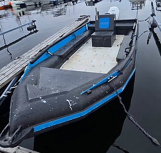 Ein schwarzes, offenes Motorboot mit blauen Akzenten schwimmt ruhig an einem hölzernen Dock. Ideal für entspannte Bootsausflüge oder Angelabenteuer auf den Malediven.