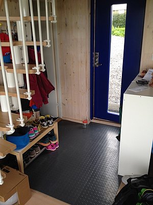 Eingangsbereich in Nordland, Norwegen mit blauer Tür, hellem Holz, Schuhregal und Regalen. Praktisch für Angelurlaub mit Schuhablage und Garderobe. Ideal zum Einstieg in ein Abenteuer in der skandinavischen Natur.