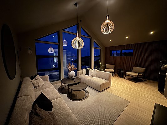 Gemütliches Wohnzimmer in Südwest-Norwegen, stilvoll eingerichtet mit großen Glasfronten, moderne Beleuchtung und bequeme Sofas, die zum Entspannen in einem skandinavischen Ambiente einladen. Ideal für Erholung nach einem erlebnisreichen Angelurlaub.