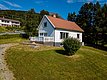 Charmantes weißes Haus in Nord-Norwegen, umgeben von üppigem Grün und Bergen. Ideal für Naturliebhaber, bietet es Ruhe und einen perfekten Ausgangspunkt für Angelabenteuer und Erkundungen in der atemberaubenden skandinavischen Landschaft.