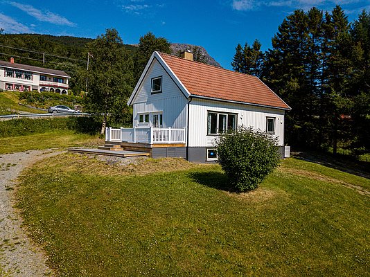 Charmantes weißes Haus in Nord-Norwegen, umgeben von üppigem Grün und Bergen. Ideal für Naturliebhaber, bietet es Ruhe und einen perfekten Ausgangspunkt für Angelabenteuer und Erkundungen in der atemberaubenden skandinavischen Landschaft.