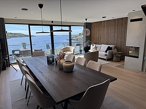 Moderne skandinavische Ferienwohnung mit Panoramafenstern, die einen atemberaubenden Blick auf die Küstenlandschaft Südwest-Norwegens bieten. Stilvolles Interieur mit Holztönen und Kamin laden zur Entspannung nach einem Angelabenteuer ein. Ideal für Angelreisen.